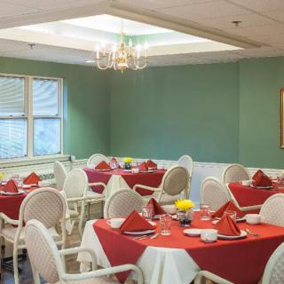 A cozy dining room with tables set with red tablecloths and neatly arranged chairs.