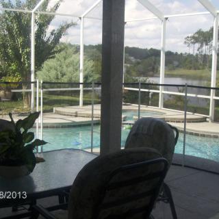 A scenic view of a pool area overlooking a lake, surrounded by a screened enclosure.