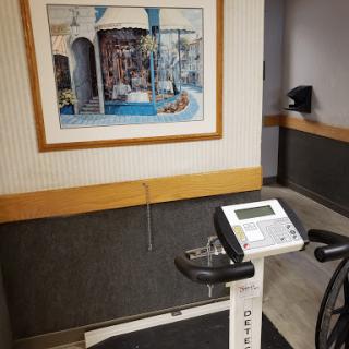 A stationary bike positioned in a healthcare facility, accompanied by an artwork on the wall.