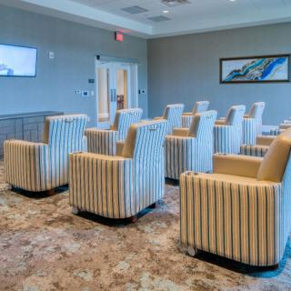 A modern lounge area featuring striped chairs and carpet flooring, arranged in a meeting room setting.