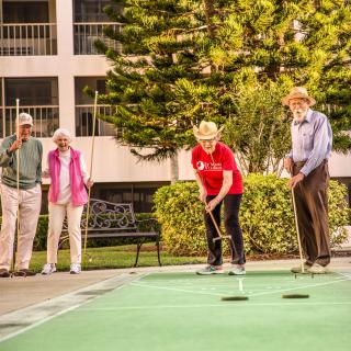 A group of seniors enjoying a game of shuffleboard outdoors.