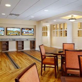 A recreational indoor space featuring mini bowling alleys with seating areas and a polished wooden floor.
