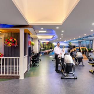 A modern gym interior featuring various exercise equipment and cardio machines, with ambient lighting.