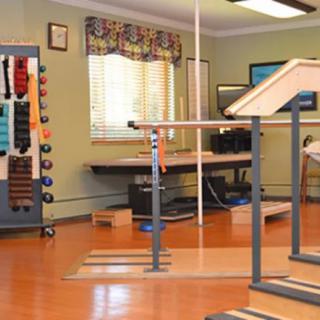 A rehabilitation room equipped with parallel bars and various exercise tools for therapy and fitness activities.