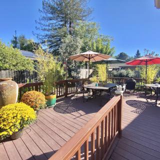 A beautiful outdoor deck area surrounded by lush greenery and vibrant flowers, perfect for relaxing in the sun.