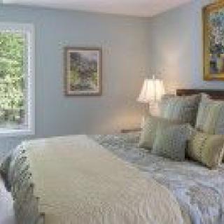 A cozy bedroom with a neatly made bed, decorative pillows, and soft lighting.