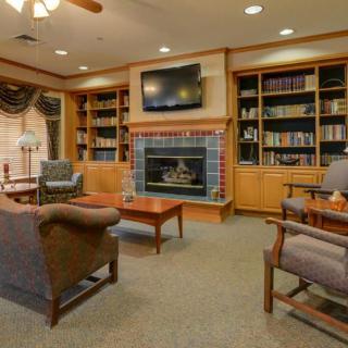 A cozy library room with bookshelves, a fireplace, and comfortable seating.