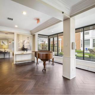 A modern interior space featuring a grand piano and large windows.