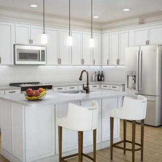 A modern kitchen with white cabinetry, featuring a central island and sleek appliances.