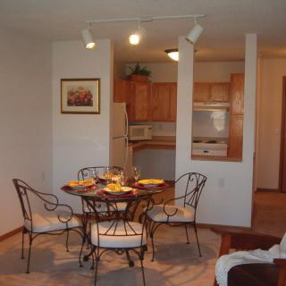 A cozy dining area with a round table and chairs, adjacent to a compact kitchen.