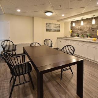 Modern dining area with a wooden table and chairs, featuring stylish lighting and kitchen space.