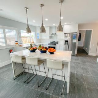 A modern kitchen with an island, featuring sleek pendant lights and bar stools.