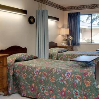 A cozy bedroom with twin beds featuring floral bedding and a window with curtains.
