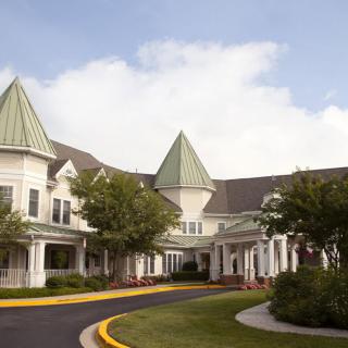 A picturesque building with green-roofed turrets surrounded by trees.
