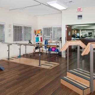 A rehabilitation clinic with exercise equipment and wooden floors.