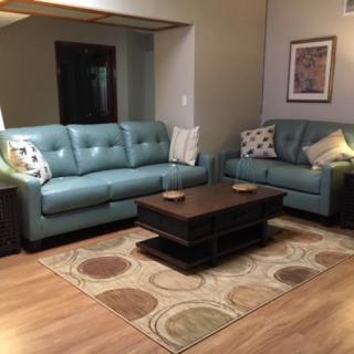 A cozy living room featuring two blue sofas, a wooden coffee table, and a patterned rug.