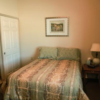 A cozy bedroom with a neatly made bed and a bedside lamp.
