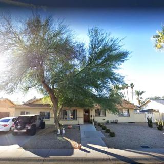 A suburban house with a driveway and cars parked outside, surrounded by trees.