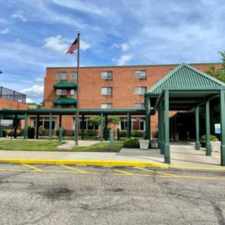 A welcoming hotel entrance with a flag flying in the background under a clear blue sky.