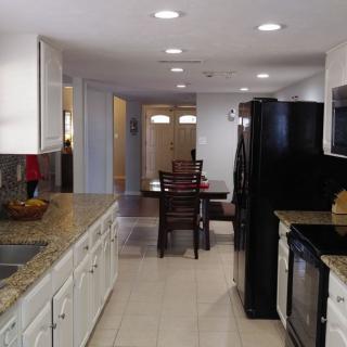 A modern kitchen with white cabinets and granite countertops opens into a dining area.