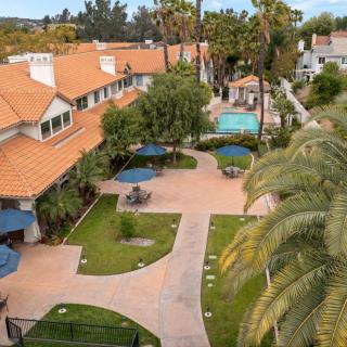 An aerial view of a hotel courtyard with pathways, palm trees, and a swimming pool.