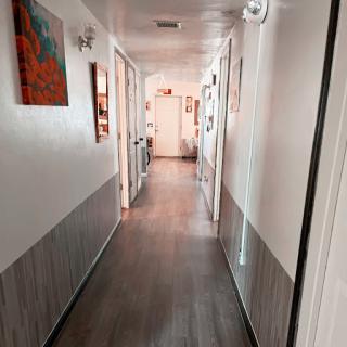A well-lit interior hallway featuring artwork on the walls and a wooden floor.