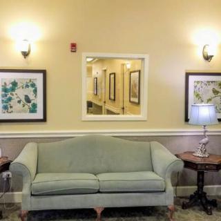 A cozy living room with a sofa, framed artwork, and a table with a lamp.