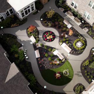 A beautifully landscaped garden featuring winding pathways, seating areas, and vibrant plants.