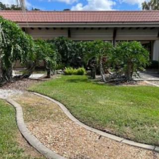 A landscaped garden with a curved gravel pathway leading to a house, surrounded by lush greenery.
