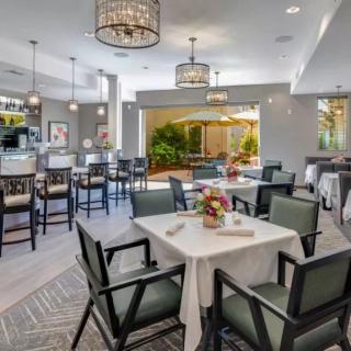 A well-decorated restaurant dining area with neatly arranged tables and chairs, featuring elegant chandeliers and floral centerpieces.