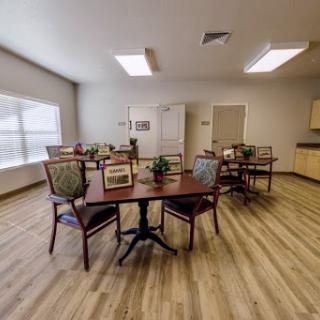 A spacious and well-lit dining area featuring multiple tables and chairs, designed for communal gatherings.