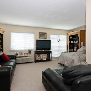 A cozy living space featuring a combination of a living room and bedroom, complete with a TV, black leather sofas, and bookshelves.