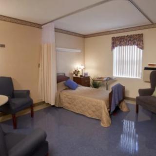 A cozy hospital room with a single bed and comfortable seating.