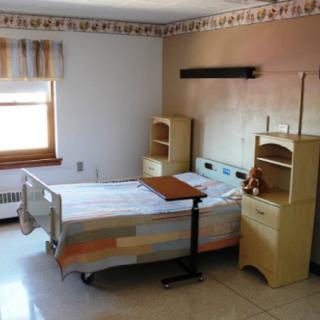 An empty hospital room with a bed and medical furniture.