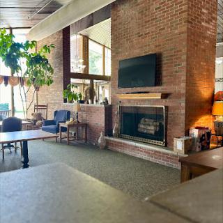 A cozy living room featuring a brick fireplace, modern furnishings, and plenty of natural light.