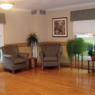 A cozy living room interior with two armchairs, decorative plants, and artwork on the wall.