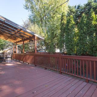 A spacious wooden deck with a covered area, surrounded by trees and a fence.