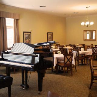 A dining room with neatly arranged tables and a grand piano.