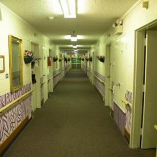 A long, carpeted hallway with fluorescent lighting and multiple doors on either side.