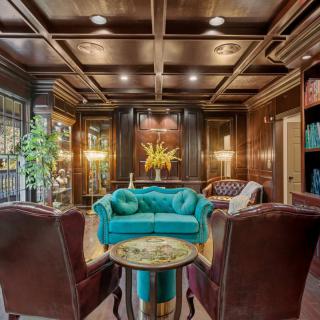 A luxurious living room with wood-paneled walls, elegant lighting, and plush furniture.