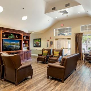 A cozy living room with leather seating, a television, and a bookshelf.