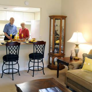 A couple preparing a meal in a cozy kitchen-living area.