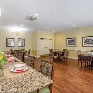 A well-arranged dining room with set tables and neatly arranged chairs.