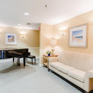 A cozy living room featuring a grand piano, a comfortable sofa, and elegant wall art.