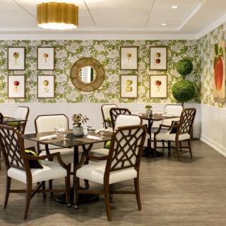 A stylish dining area with floral wallpaper and elegant wooden furniture.