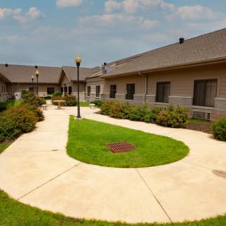 A well-maintained courtyard with pathways, grass, and surrounding buildings under a cloudy sky.