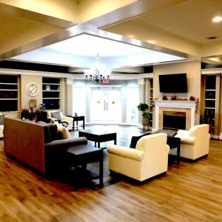A modern living room with comfortable seating, a television above the fireplace, and elegant wood flooring.