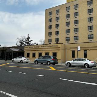 A view of a hospital building with parked cars in the foreground.