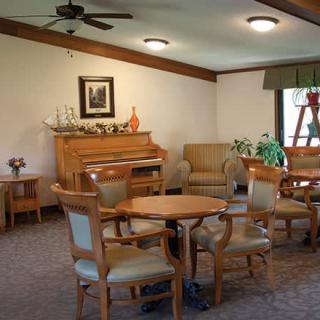 A cozy living room with wooden furniture, a piano, and decorative plants.