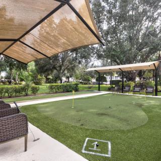 A relaxing outdoor patio with seating and shade canopies surrounded by greenery.